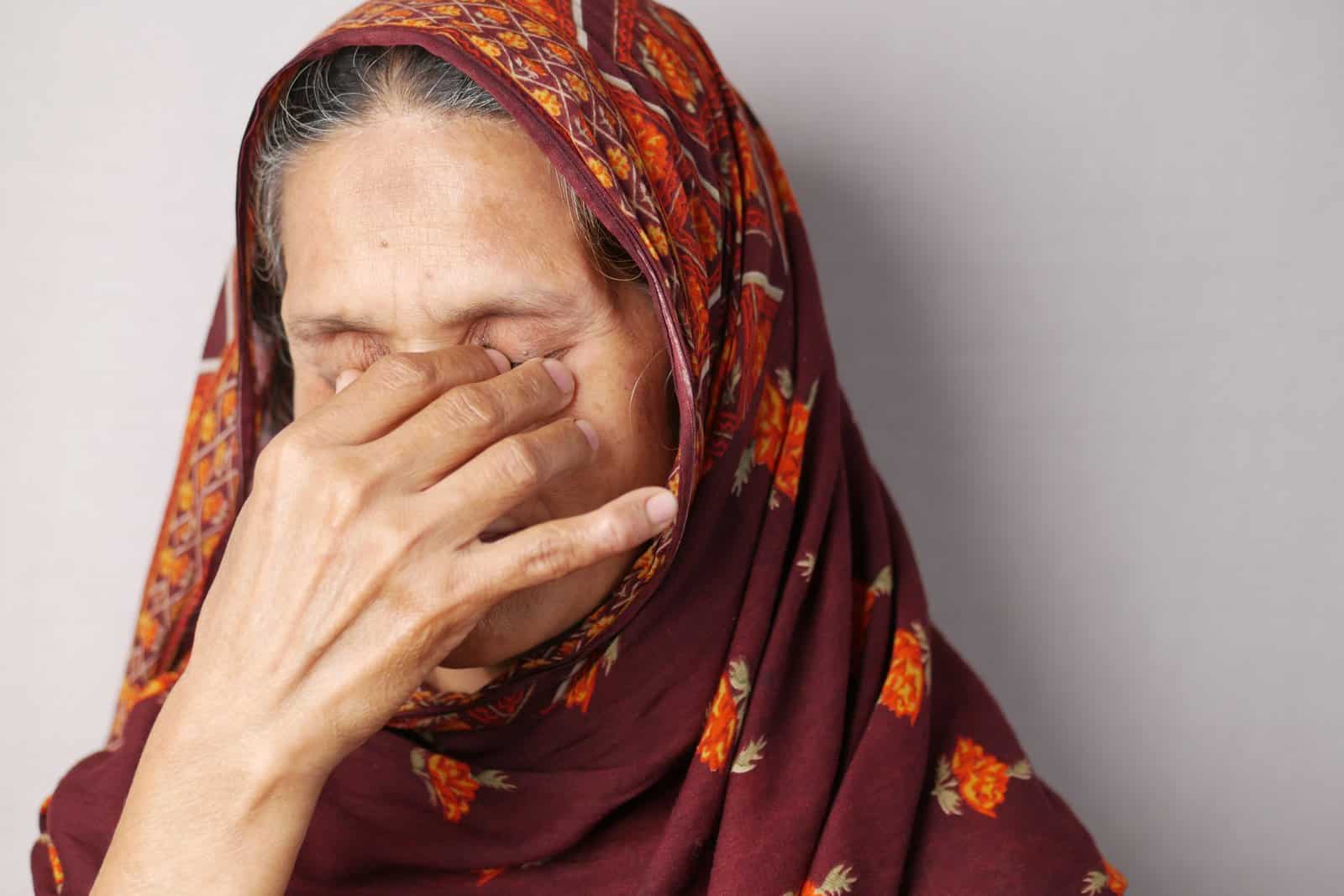 Woman pinching the bridge of her nose with eyes closed in migraine pain