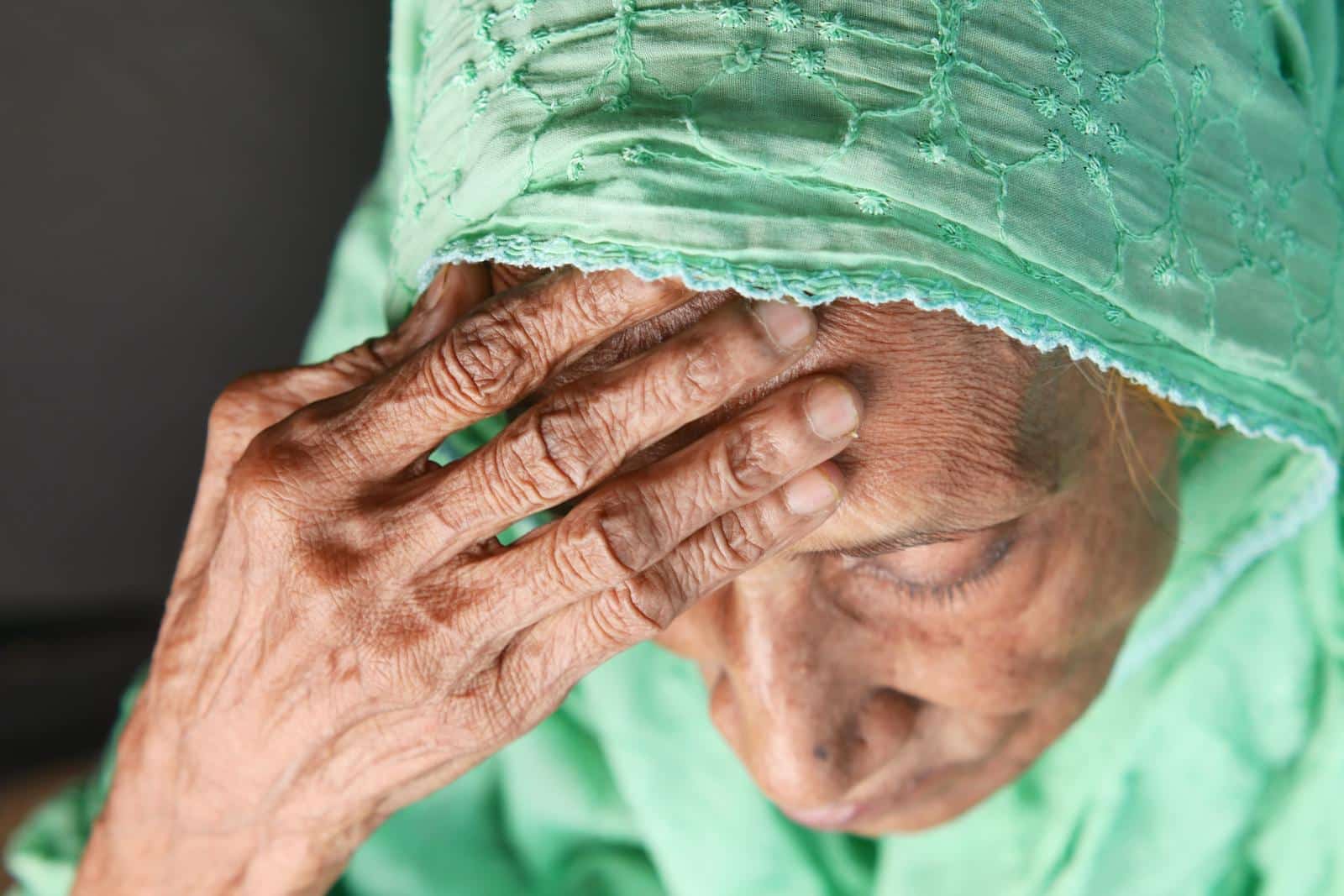 Close-up of an elderly woman holding her forehead in discomfort