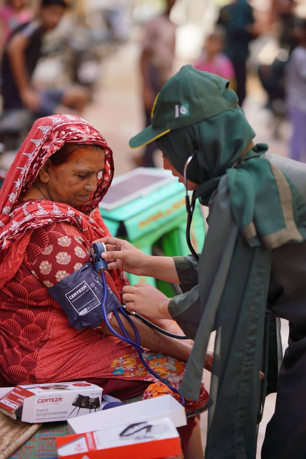 An SIEHS 1122 responder checking an elderly woman's blood pressure in the field
