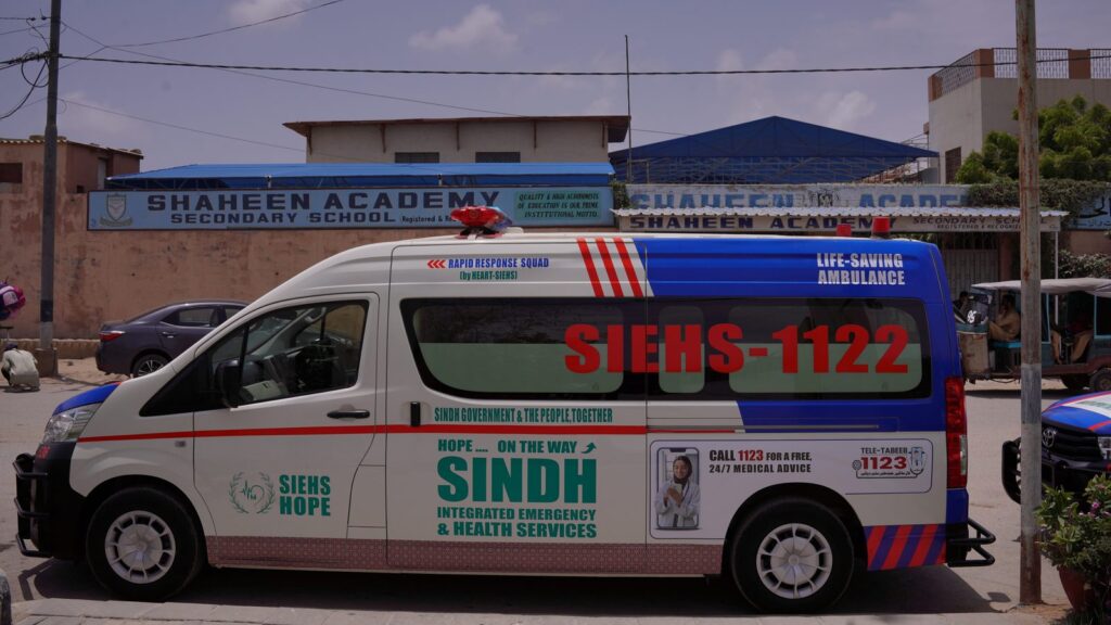 SIEHS 1122 ambulance parked outside a school in a narrow, unnumbered Karachi lane