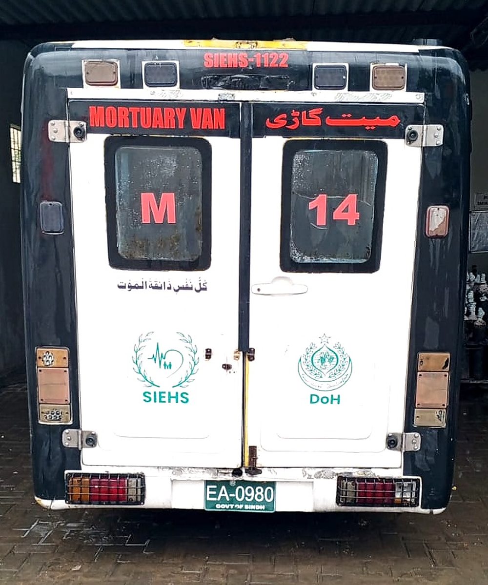 Rear doors of a SIEHS 1122 mortuary van, unit M 14, marked MORTUARY VAN in English and meyat gaari in Urdu, with the SIEHS and Health Department crests.