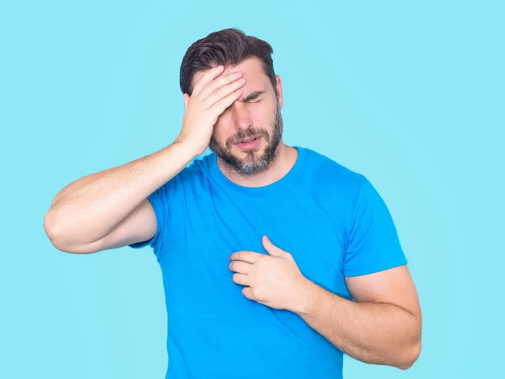 Man holding his forehead in pain with eyes shut, illustrating concussion symptoms after a head injury