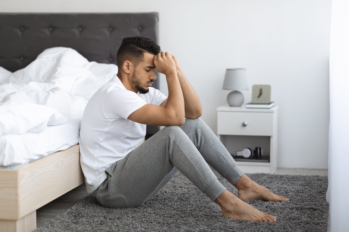 Man sitting on a bedroom floor with his head in his hand during dizziness aur ghabrahat