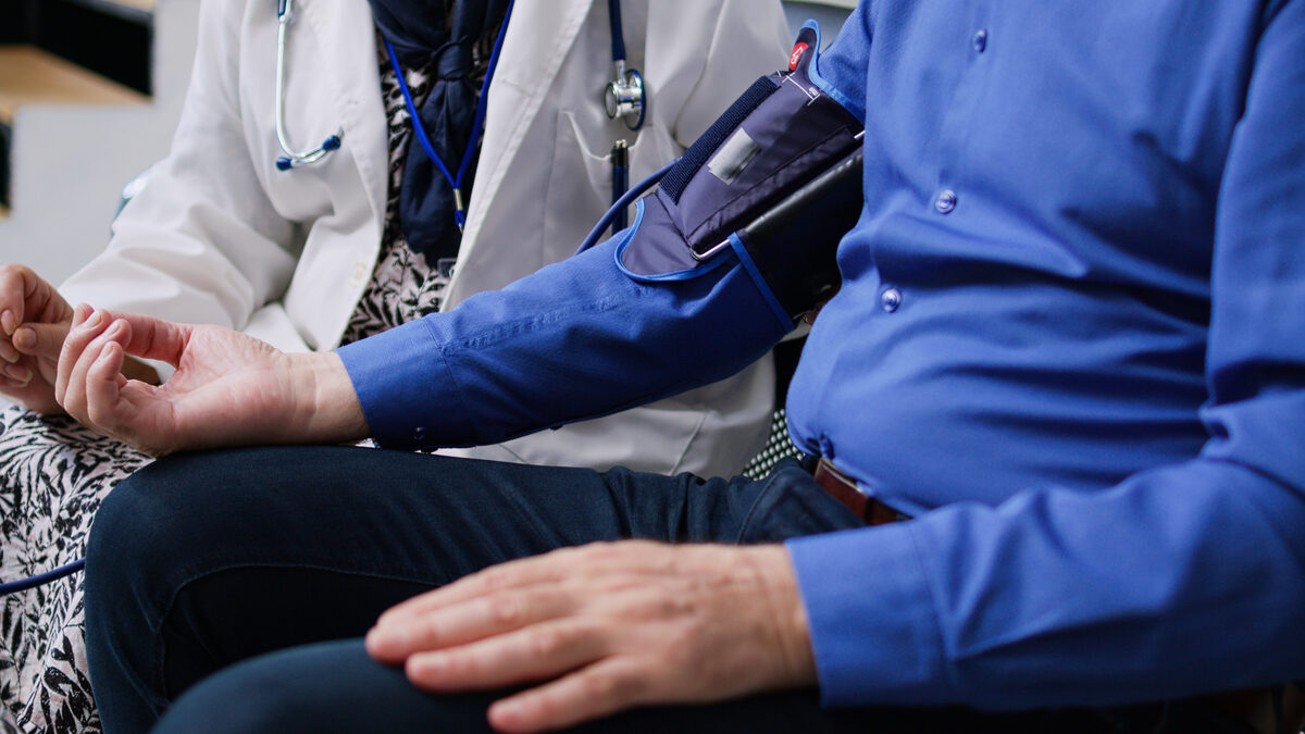 Doctor with stethoscope checking a patient's blood pressure in a hospital setting