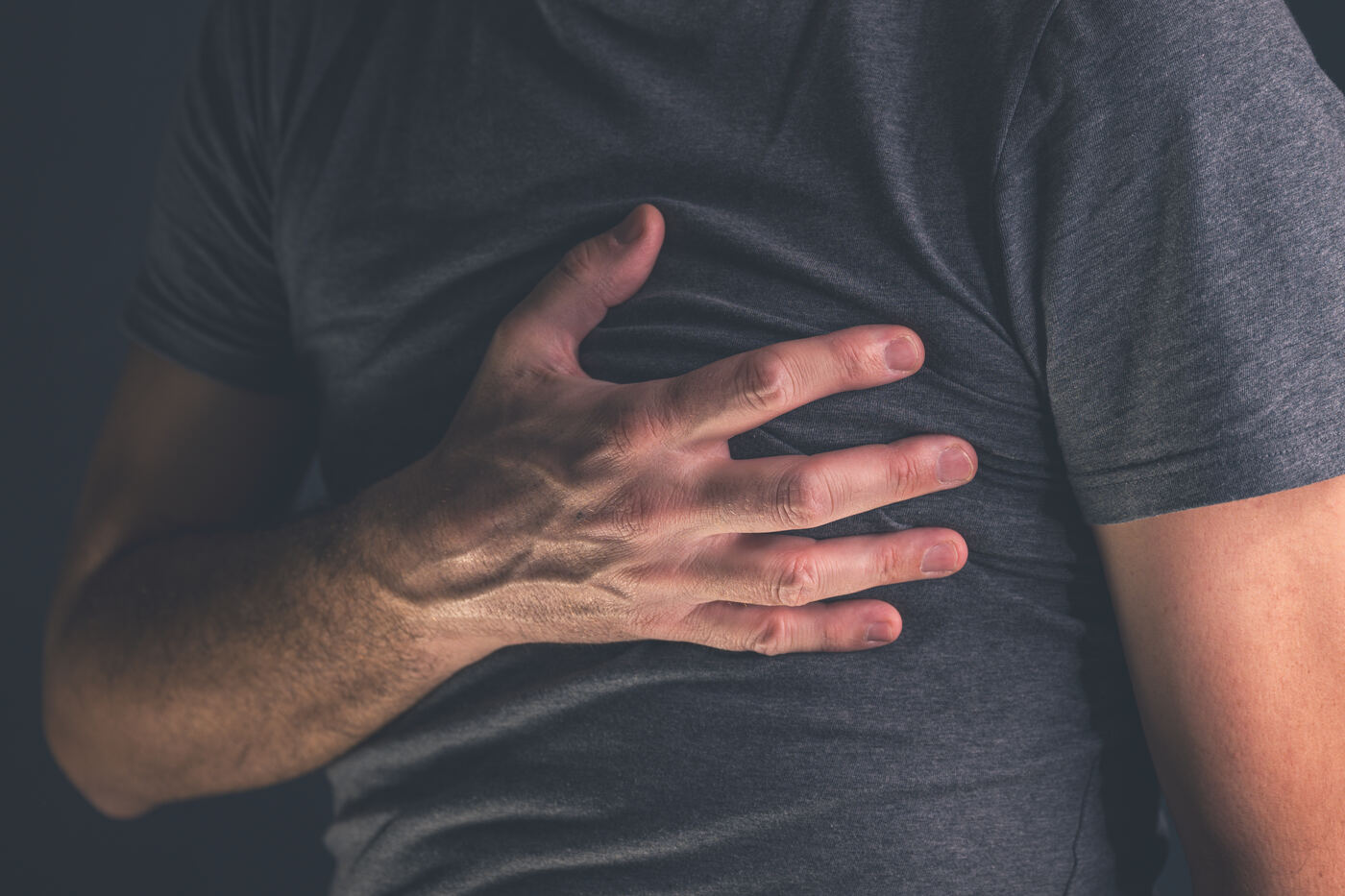 Man clutching his chest in pain, heart attack symptom