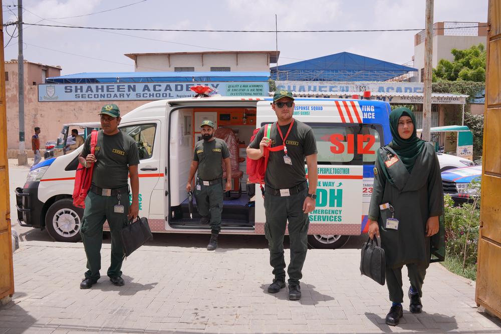 SIEHS 1122 emergency response team standing with their ambulance outside Shaheen Academy in Sindh, ready to respond to a call