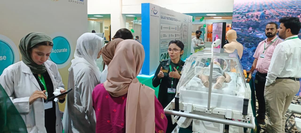 Visitors and a SIEHS paramedic gathered around the neonatal incubator display at Health Asia 2026