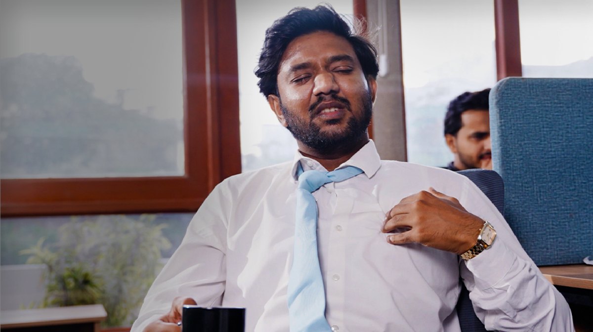 Man at office desk holding his chest in discomfort, a situation where you should call SIEHS 1122 immediately