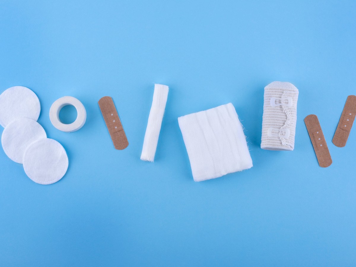 Cotton pads, tape, plasters, gauze and an elastic bandage laid out for a first aid kit check