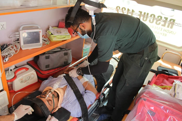 SIEHS 1122 paramedic caring for a patient with a neck collar and oxygen mask inside an ambulance