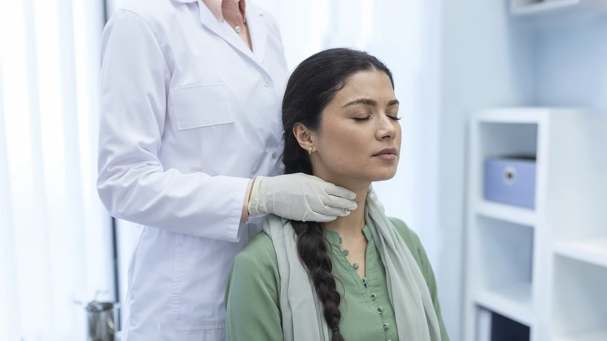 A doctor gently checks the neck of a woman patient for thyroid problems in a clinic