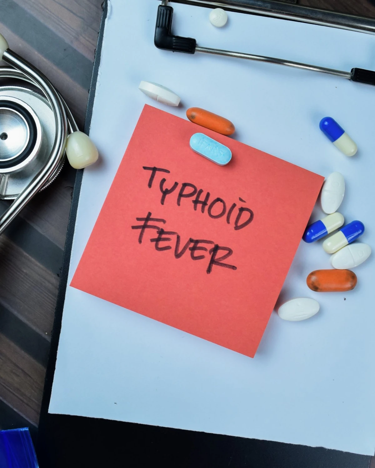 Typhoid fever diagnosis, clipboard with handwritten note, stethoscope and prescription medicines