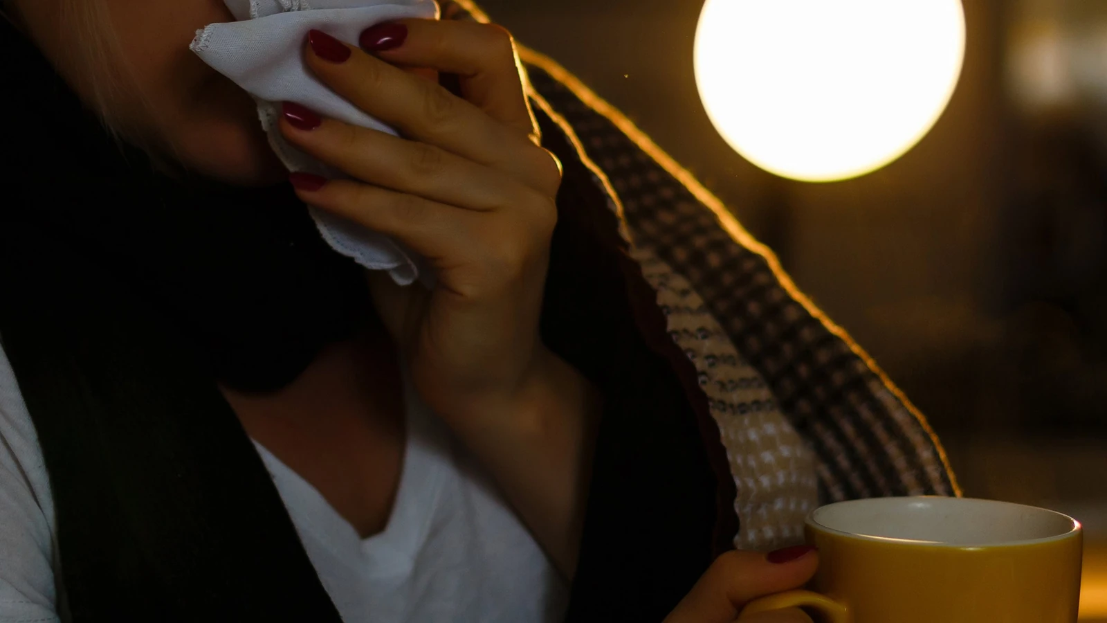 Weather change flu symptoms in Pakistan, person at home with warm drink and tissue